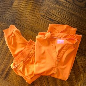 Vibrant Orange Women's scrub top with joggers.